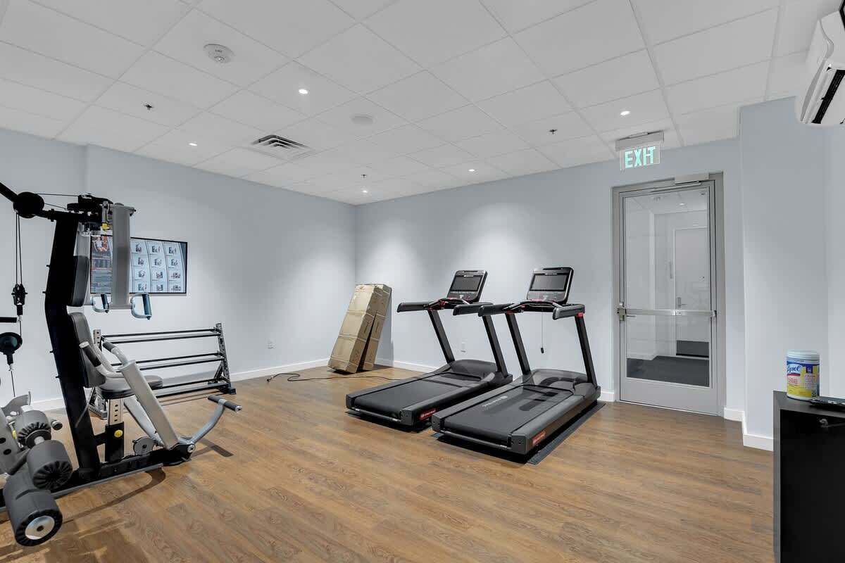 Community gym with treadmills, strength-training equipment, workout benches, storage racks, and open space for exercise.