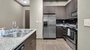 Una cocina moderna con electrodomésticos de acero inoxidable, encimera de granito y armarios de madera.