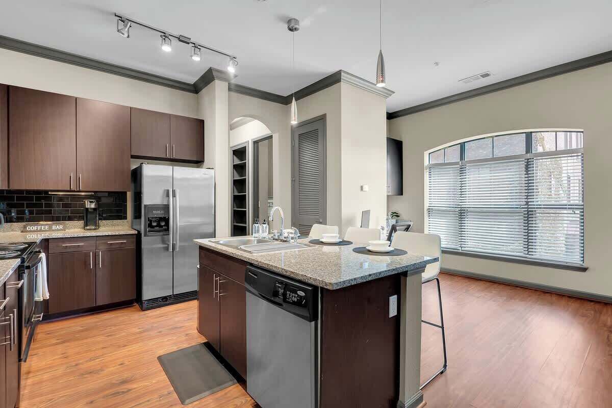 A modern kitchen with dark wood cabinets, stainless steel appliances, and a granite countertop.