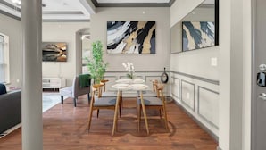 A modern dining area with a round table, four chairs, and abstract wall art.