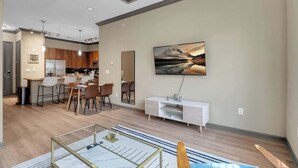 Un saló modern amb zona de menjador, cuina i un quadre gran a la paret.