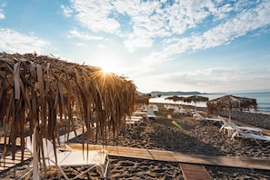 Una spiaggia nelle vicinanze, sabbia scura, lettini da mare, ombrelloni