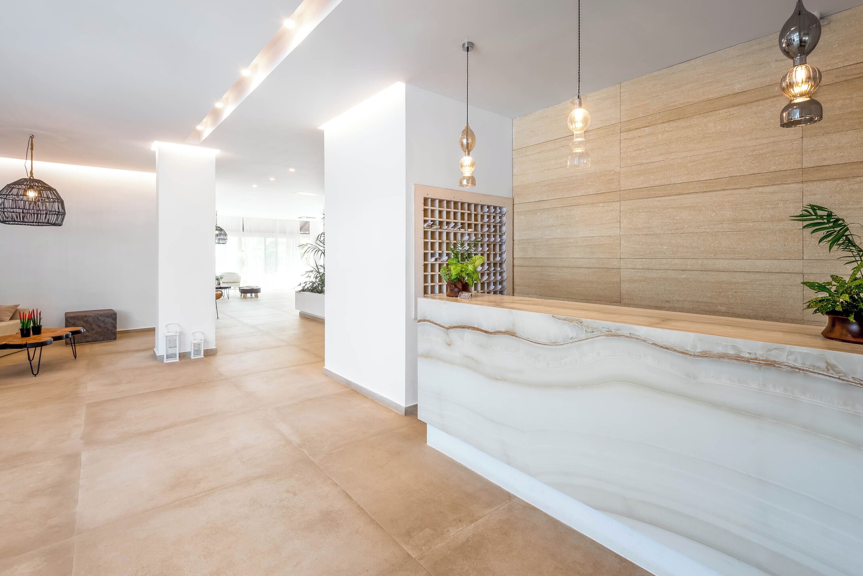 A modern reception area with a marble counter, wooden panel wall, and pendant lighting.
