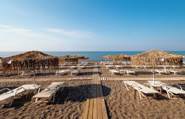 In Strandnähe, schwarzer Sandstrand, Liegestühle, Sonnenschirme