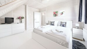 A modern bedroom with a bed, bedside tables, a TV, and artwork on the wall. - Dom Marcello Sun & Snow  (gmina Wolin)