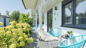 A covered outdoor area with white wicker chairs, a small table, and a potted plant. - Dom Marcello Sun & Snow  (gmina Wolin)