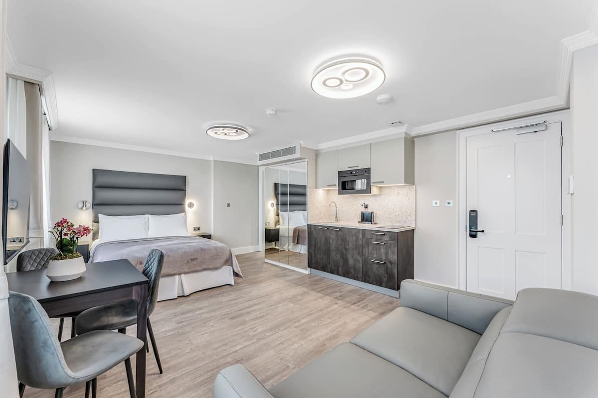 Camera d'albergo moderna con un letto, una scrivania, una sedia, un divano, angolo cottura e bagno.