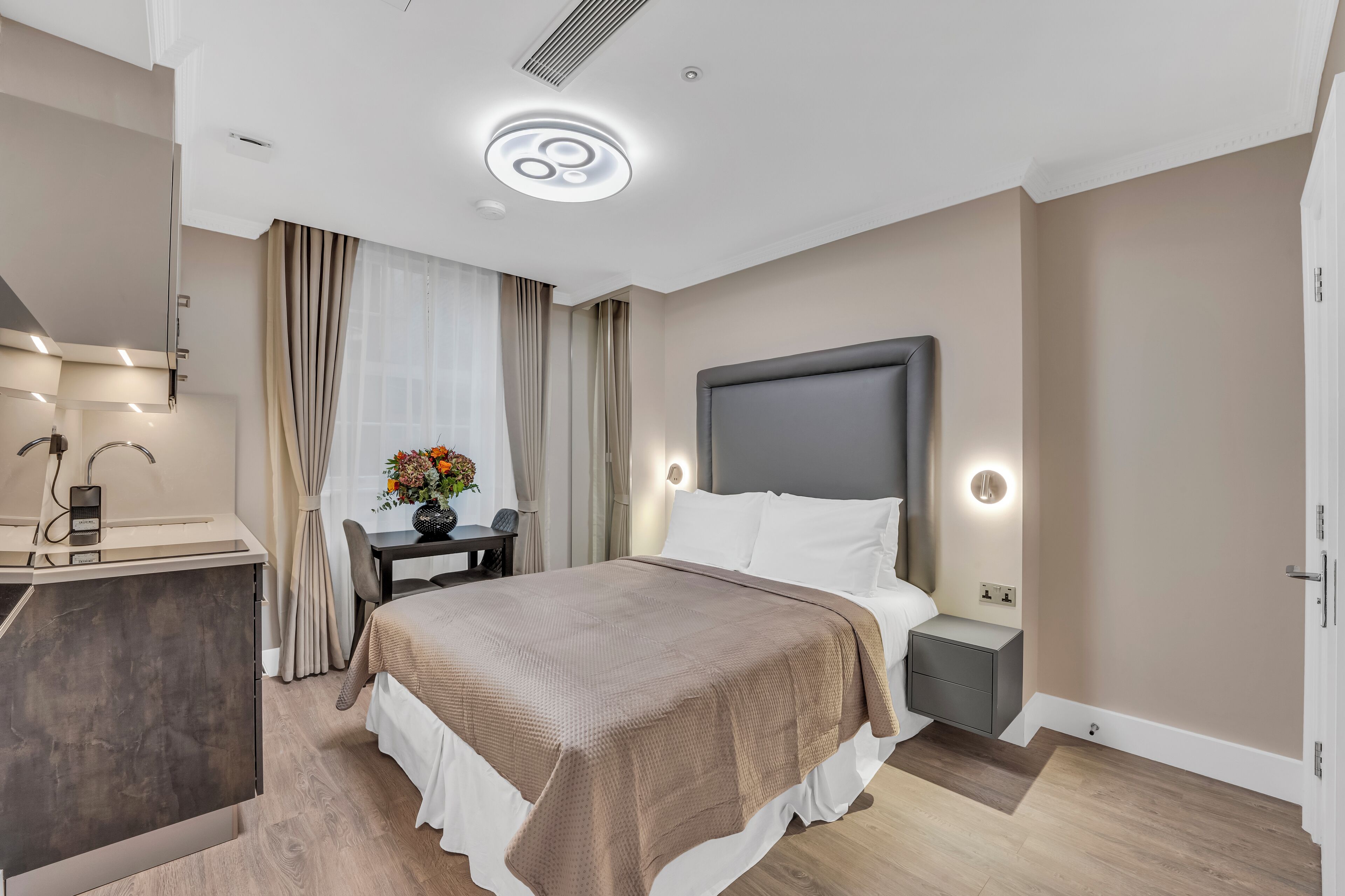 Ein modernes Hotelzimmer mit einem großen Bett, Nachttischen, einem Schreibtisch und einem Sessel.