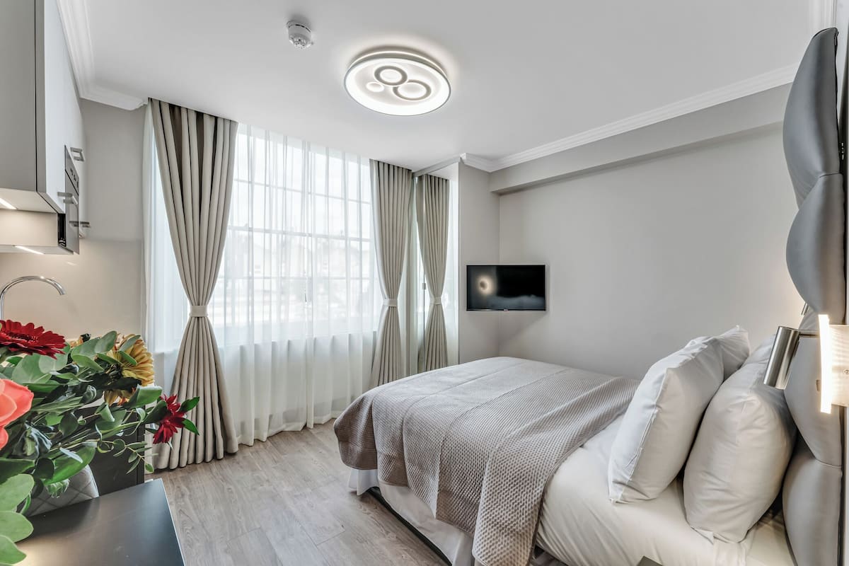 Una camera da letto moderna con un letto, tende, una TV a schermo piatto e un lampadario.