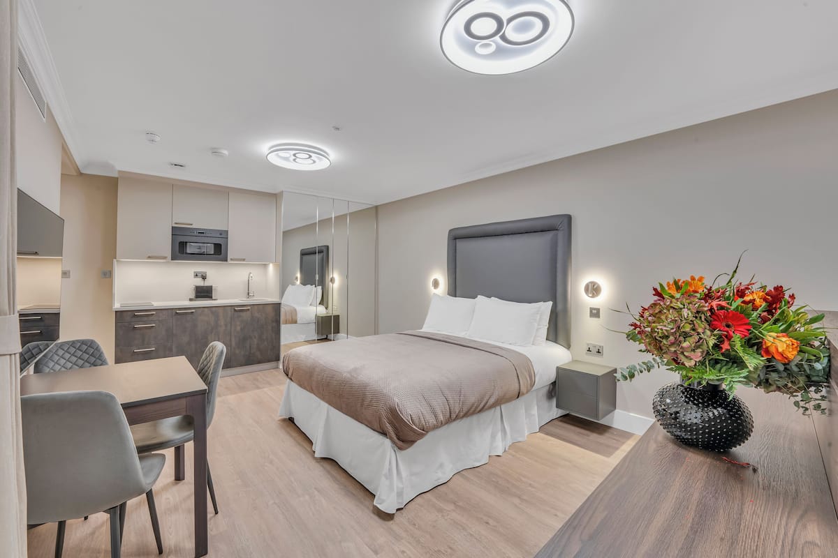 Una camera d'albergo moderna con un letto, un comodino e un vaso di fiori.