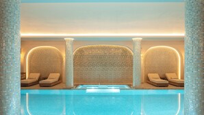 Ein Wellnessbereich mit Pool, Liegestühlen und Wandgestaltung aus Mosaiken.
