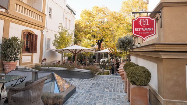 An outdoor seating area with tables and chairs, a fountain, and potted plants. - Vila Ebel Hotel Pool & Spa (Korçë)