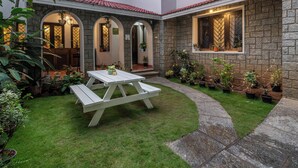Une maison avec une façade en pierre, un toit blanc et une pelouse bien entretenue.