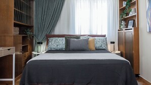 A neatly arranged bedroom with a large bed, a bedside table, a wardrobe, and a window with curtains. - Neos Kosmos Gem w Acropolis View Balcony (Athens)