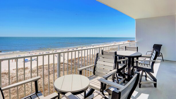 A balcony with a view of the beach and ocean. There are several chairs and a table. - Lighthouse 506 by Liquid Life (Gulf Shores)