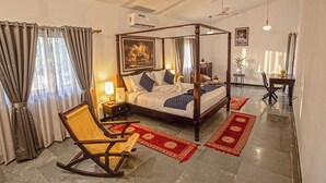 A four-poster bed with a wooden frame, a rocking chair, and a red and gold patterned rug. - The Stay Ranakpur (Desuri)