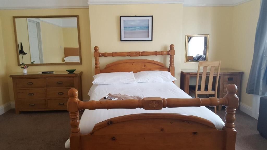 Ein Schlafzimmer mit einem hölzernen Bett, einem Schminktisch, einem Stuhl und einem Schreibtisch.