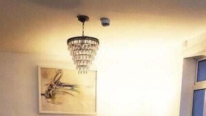 A living room with two leather sofas, a wooden coffee table, a chandelier, and a painting on the wall. - The Beacon Hotel (Redcar)