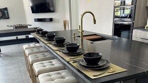 Een moderne keuken met een centraal eiland, barstoelen en een ingebouwde oven.