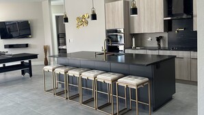 Een moderne keuken met een centraal eiland, barkrukken en hanglampen.