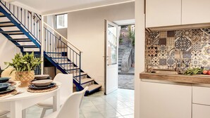 A modern kitchen with a tiled backsplash, a built-in sink, and a dining area with a table and chairs. - Casetta Di Laura In Massa Lubrense (Massa Lubrense)