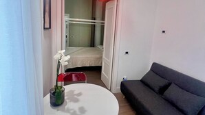 Una sala moderna con una mesa redonda blanca, un sofá gris oscuro y una lámpara colgante roja.