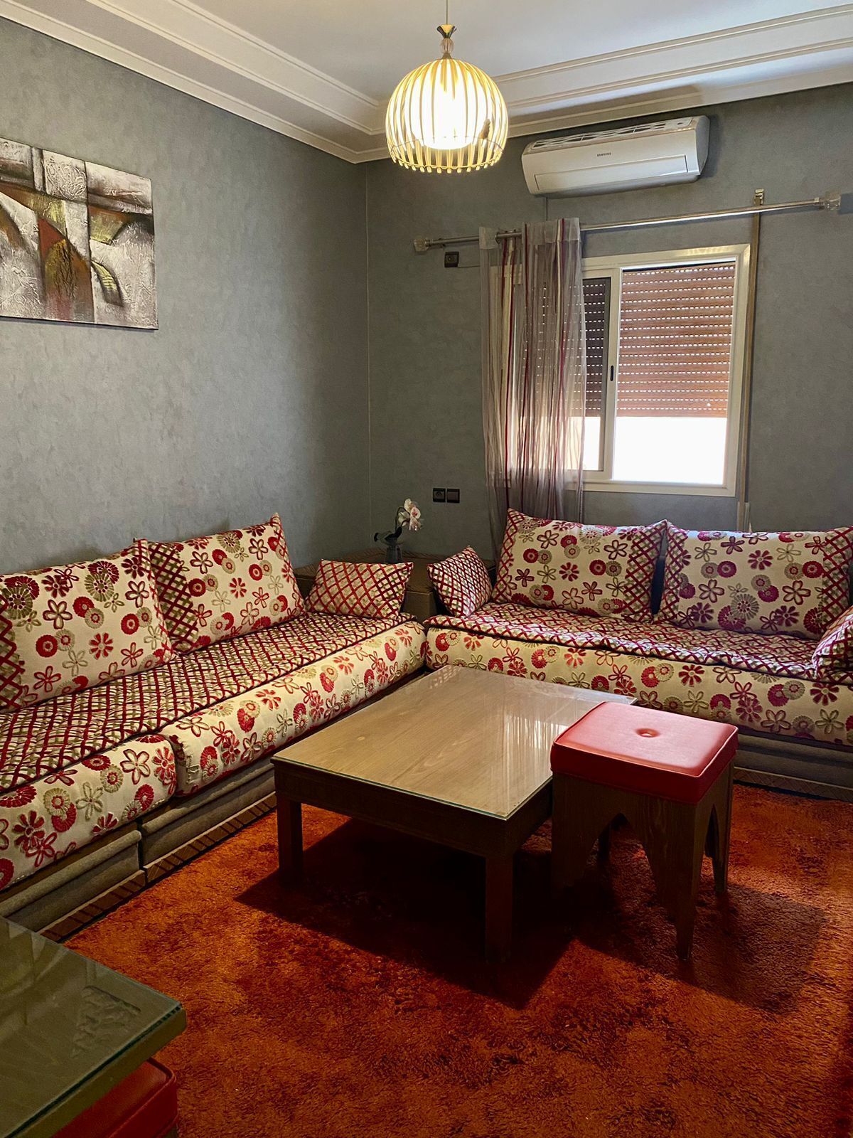 Uma sala de estar com sofá, mesa de centro e luminária pendente.