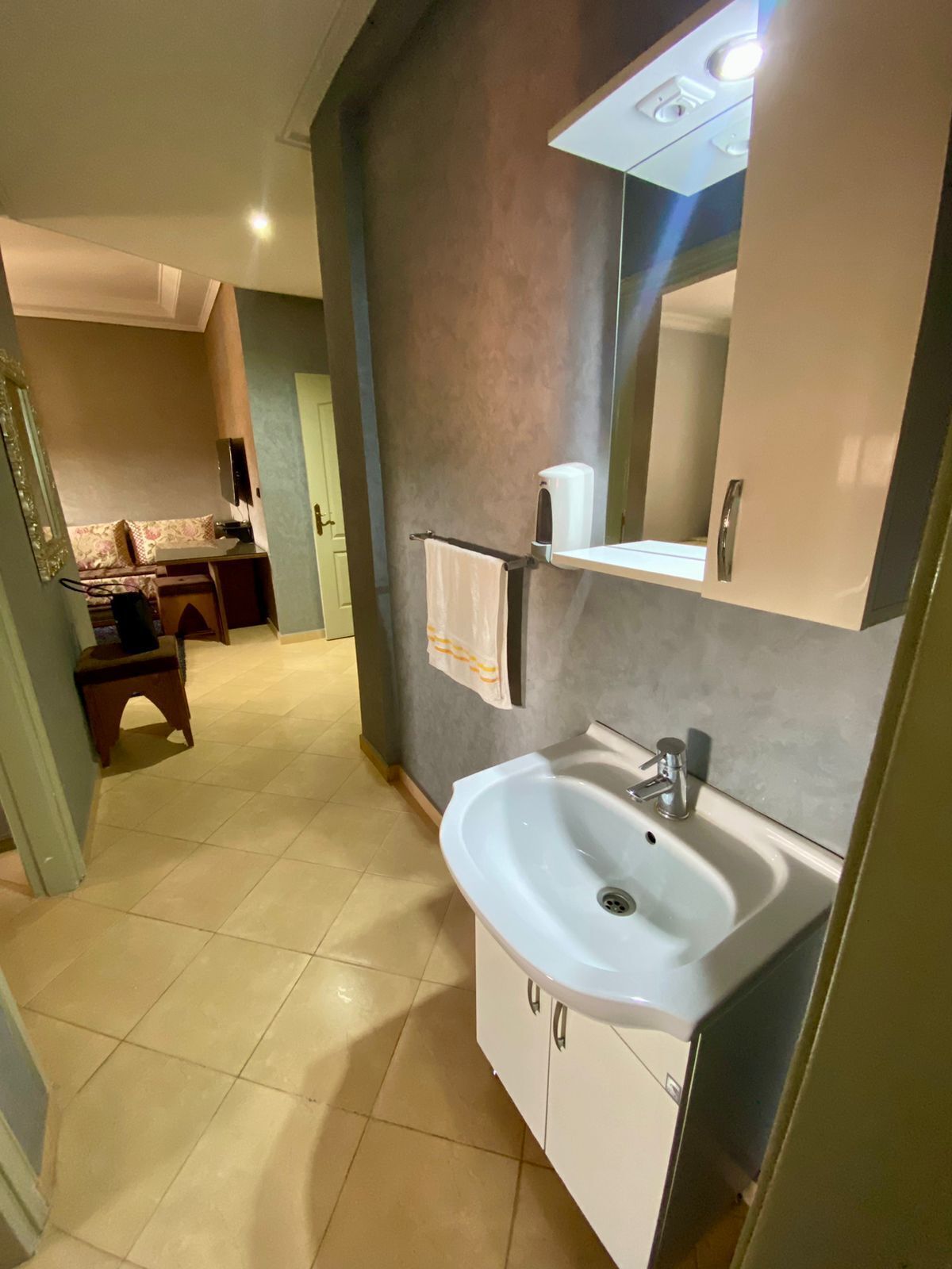 A modern bathroom with a white sink, a mirror, and a towel rack.