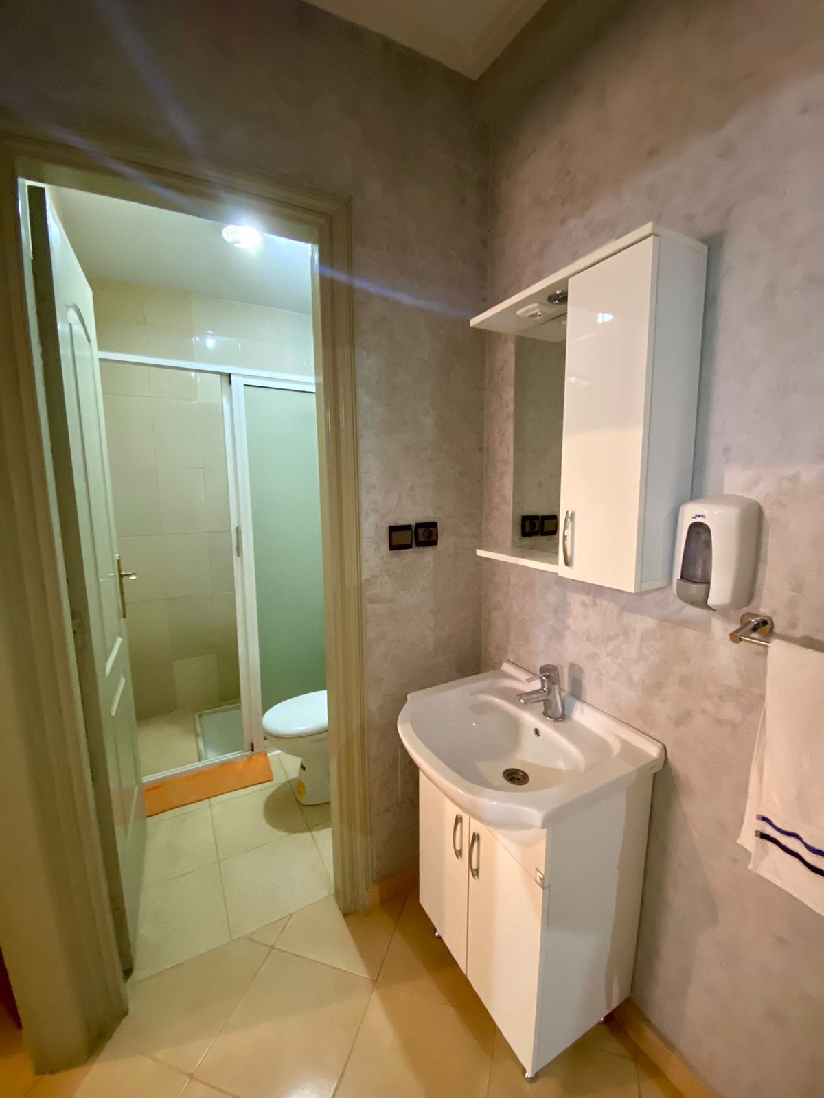 Un baño con lavamanos, espejo y retrete blancos.