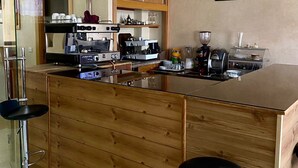 Eine moderne Küche mit einer Holzinsel, Barhocker und diversen Geräten.