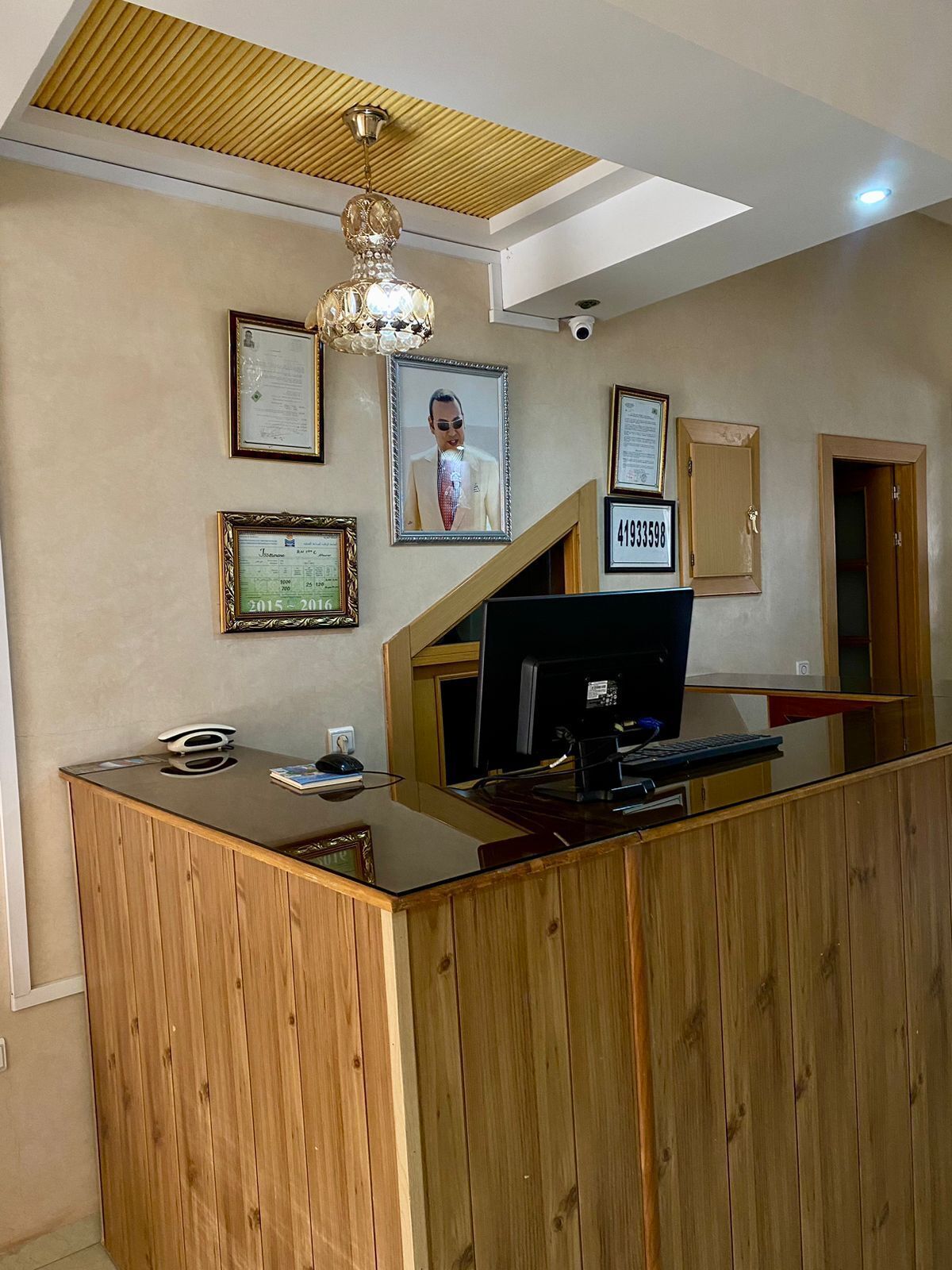 A reception desk with a computer, framed certificates, and a security camera.