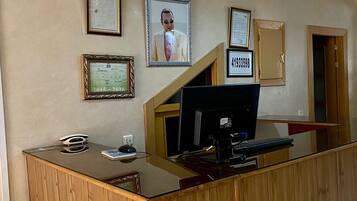 A reception desk with a computer, framed certificates, and a security camera.