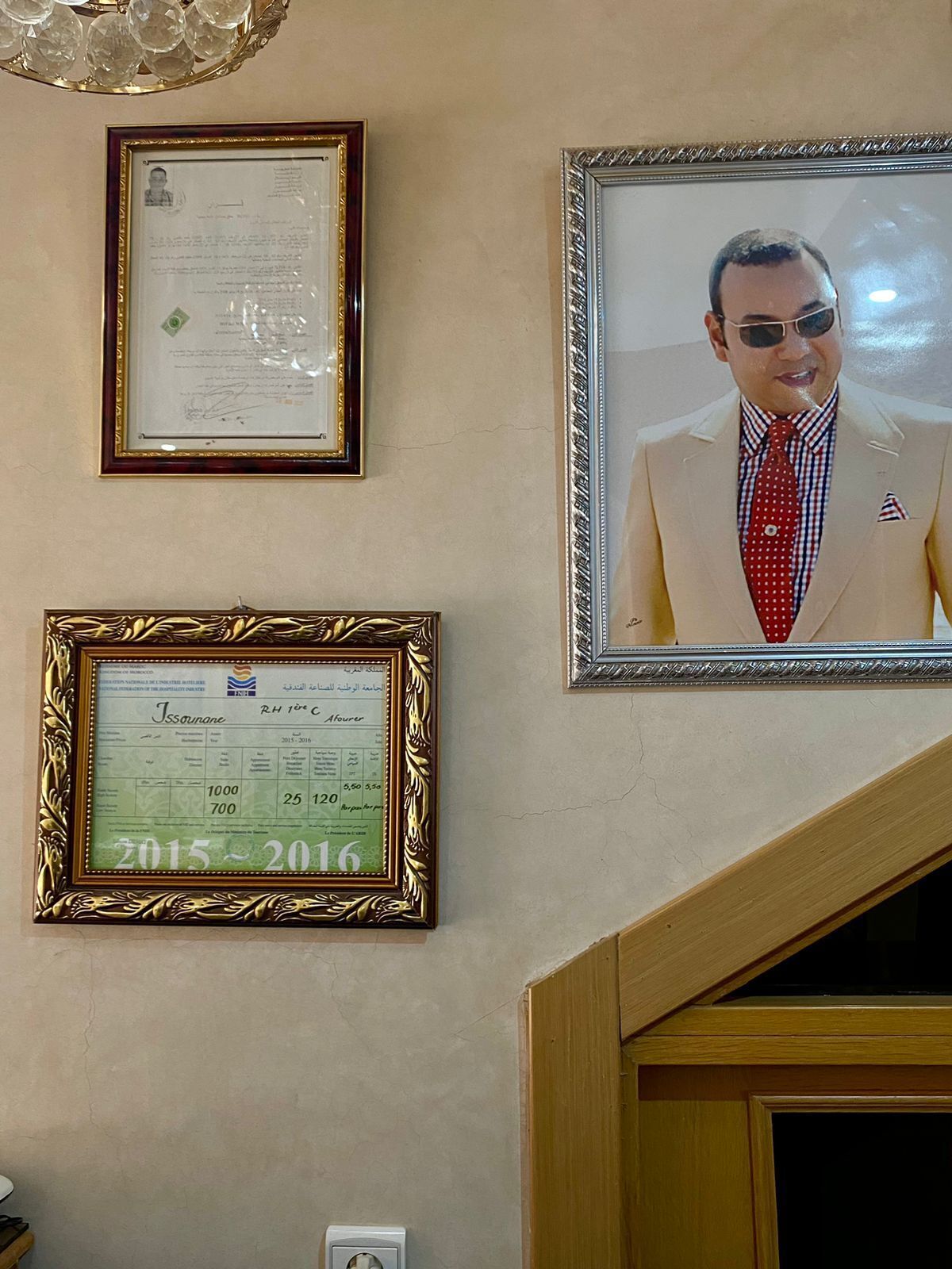 Eine Wand mit drei gerahmten Objekten: einem Zertifikat, einer Scheck und einem Foto.