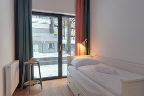 Una camera da letto con un letto, una sedia, un termosifone e vista all'esterno.