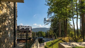 A residential area with a stone building, a paved pathway, and a view of mountains in the distance. - RentPlanet - Źródło Izery (Swieradow-Zdroj)