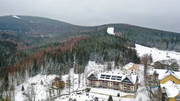 A snow-covered mountain with a ski resort, including buildings with balconies and a ski lift.