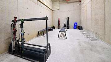 Un gimnasio con una banca, equipamiento de ejercicio y un soporte de pared para esquíes.