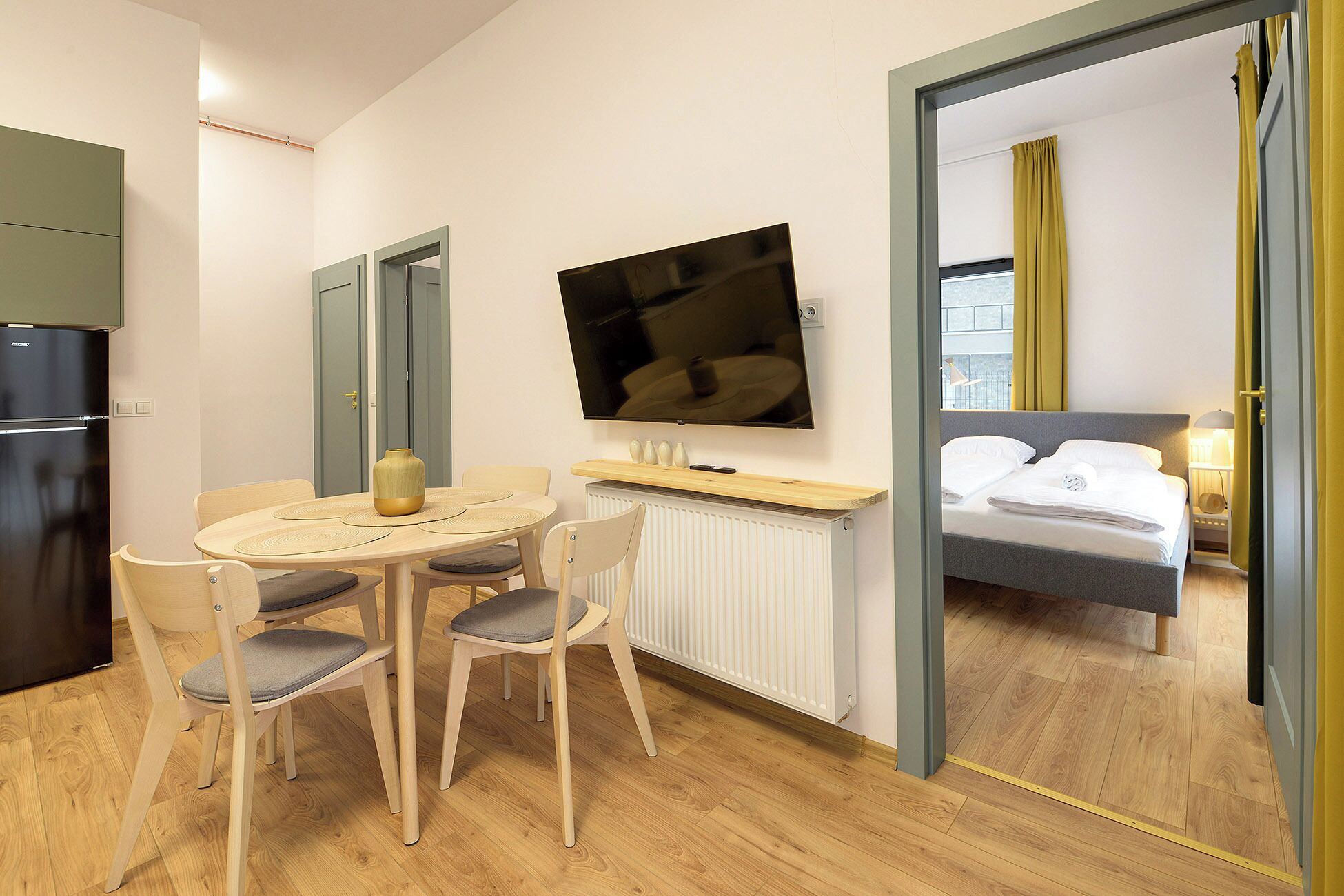 A hotel room with a dining area, a bed, and a TV.