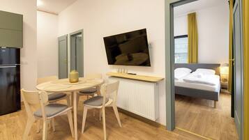 A hotel room with a dining area, a bed, and a TV.