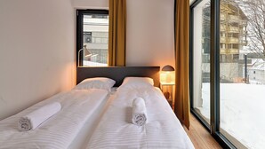 A hotel room with two beds, a large window, and a view of a snowy outdoor area. - RentPlanet - Źródło Izery (Swieradow-Zdroj)