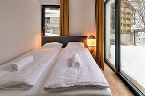 A hotel room with two beds, a large window, and a view of a snowy outdoor area. - RentPlanet - Źródło Izery (Swieradow-Zdroj)