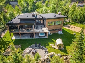 A modern two-story house with a large deck, a hot tub, and a well-maintained lawn.
