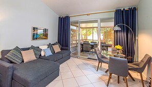 Una sala de estar con sofá, sillas, una mesa y un ventanal de vidrio que da a un espacio exterior.