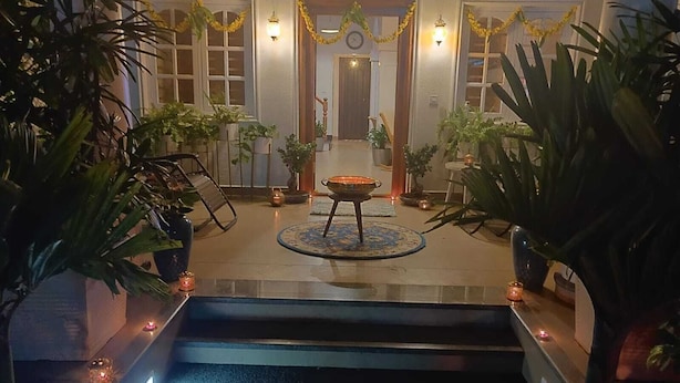 Un hall de hotel con un área de descanso central, una escalera que sube a un piso superior y plantas en macetas a lo largo de las paredes.