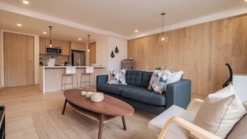 A modern living room with a sofa, coffee table, and a kitchen in the background.