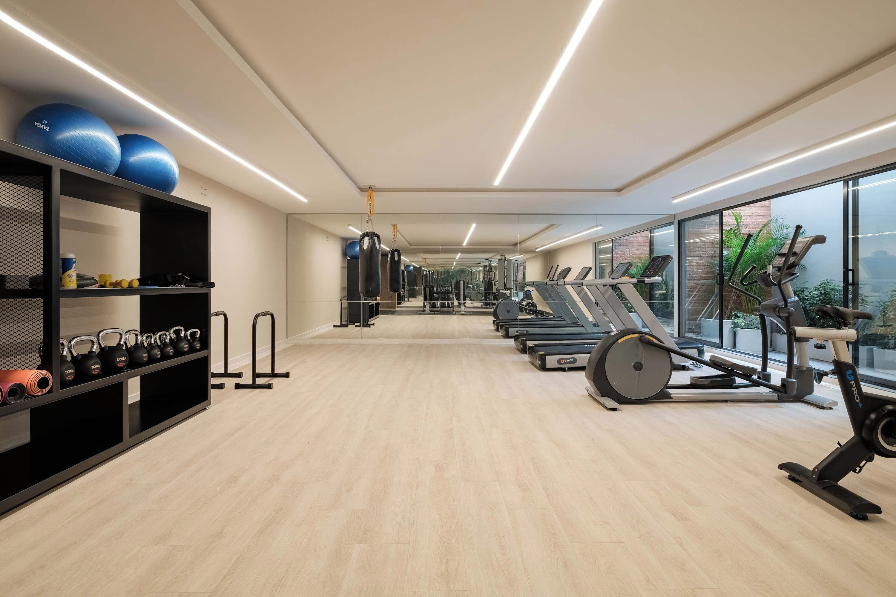 A modern gym with exercise equipment, a mirrored wall, and a view of the outdoors.