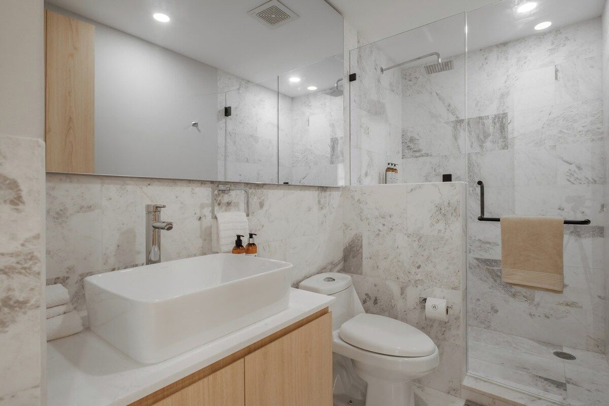A modern bathroom with a large bathtub, a toilet, and a glass-enclosed shower area.