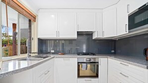 Eine moderne Küche mit weißen Schränken, einem eingebauten Backofen und einer Edelstahl-Dunstabzugshaube.