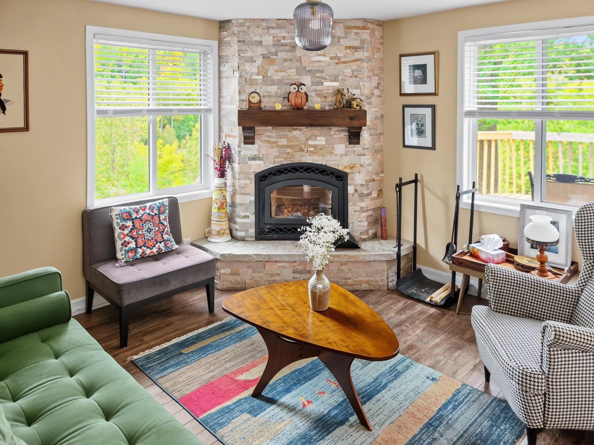 A living room with a stone fireplace, a sofa, a coffee table, and a houndstooth armchair.
