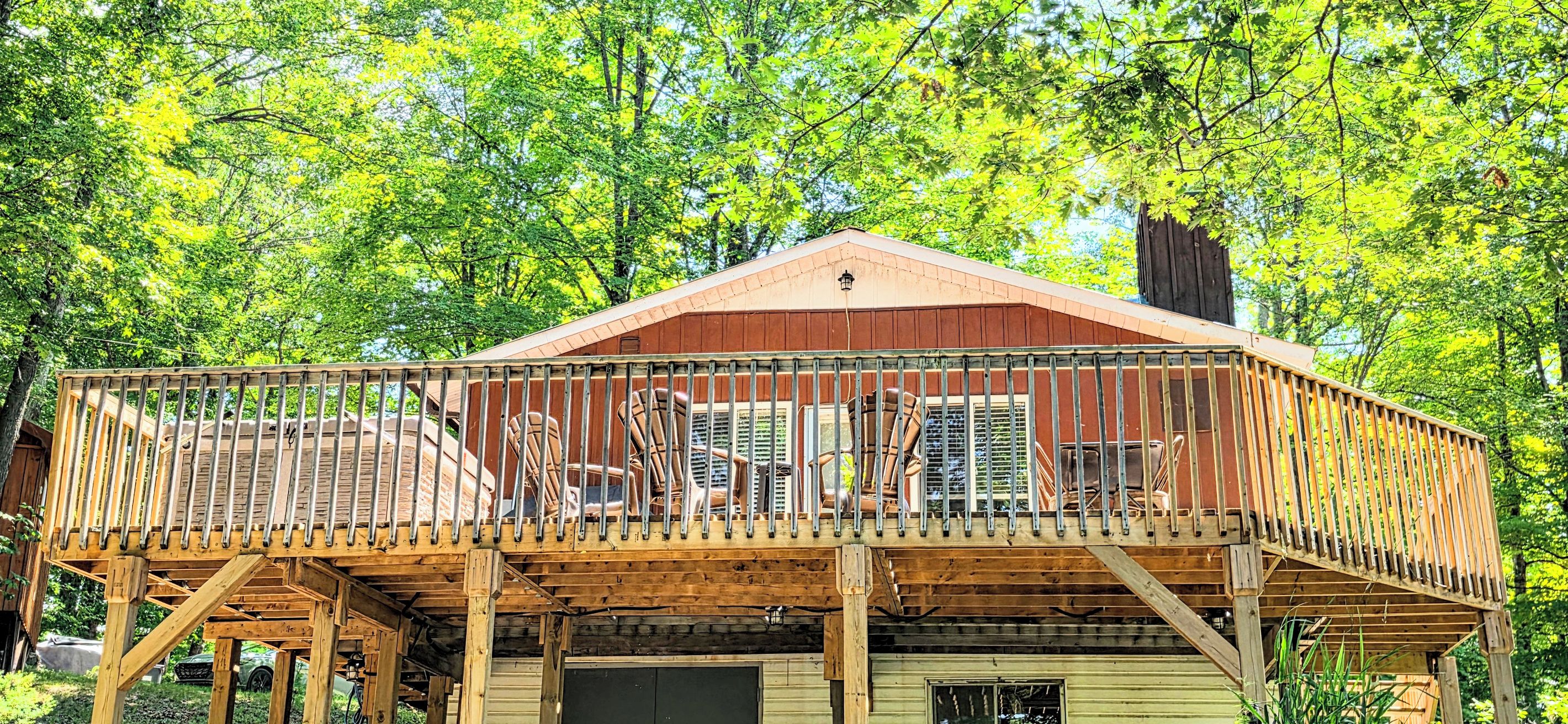 A wooden cabin with a balcony, surrounded by trees.